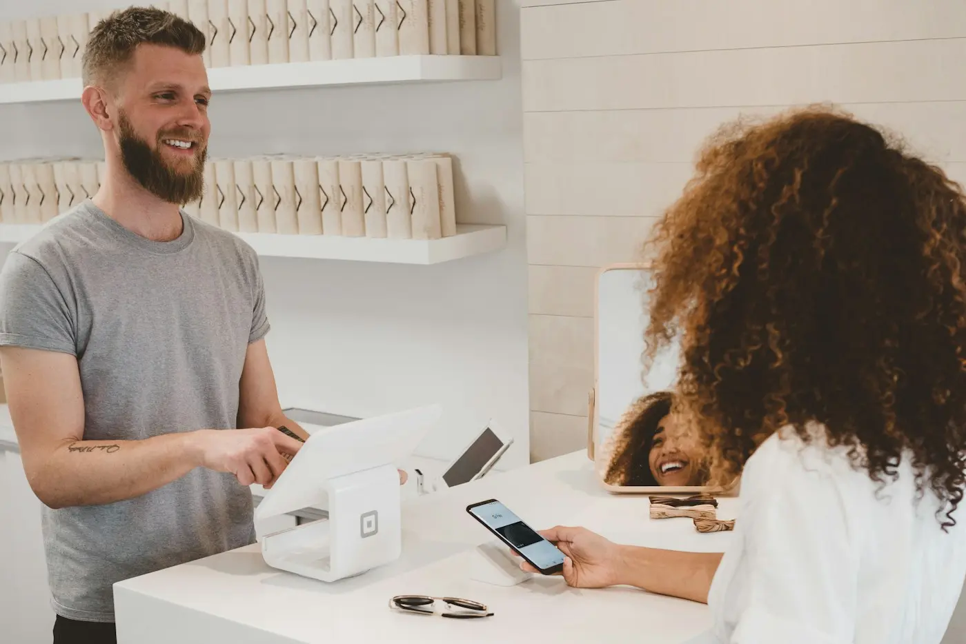 Dueño de un comercio atendiendo a una clienta en el mostrador