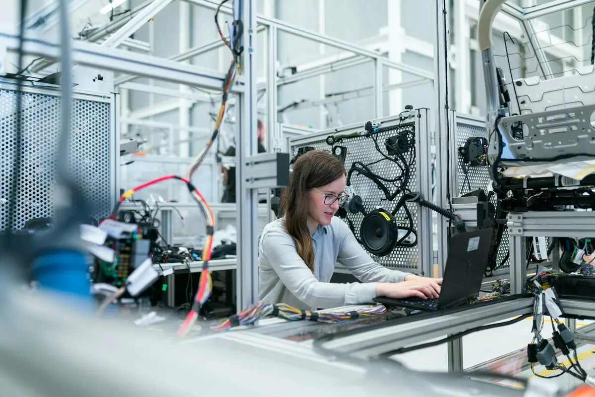 Technician working on a laptop next to an industrial machine